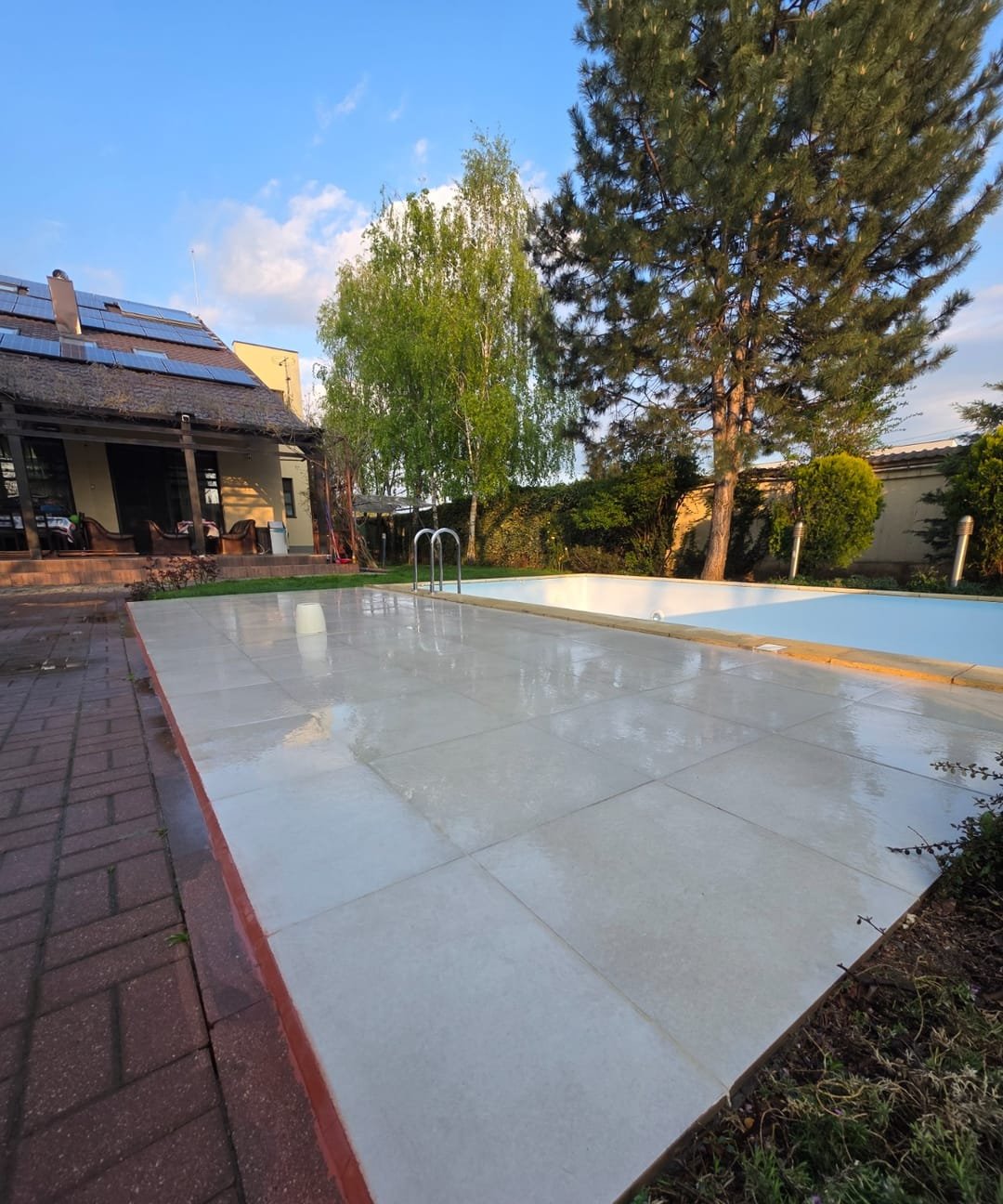Aceeași terasă după renovare: gresie de exterior format mare, rosturi drepte, piscină curată